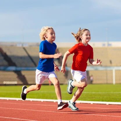 Two children running on a track field.